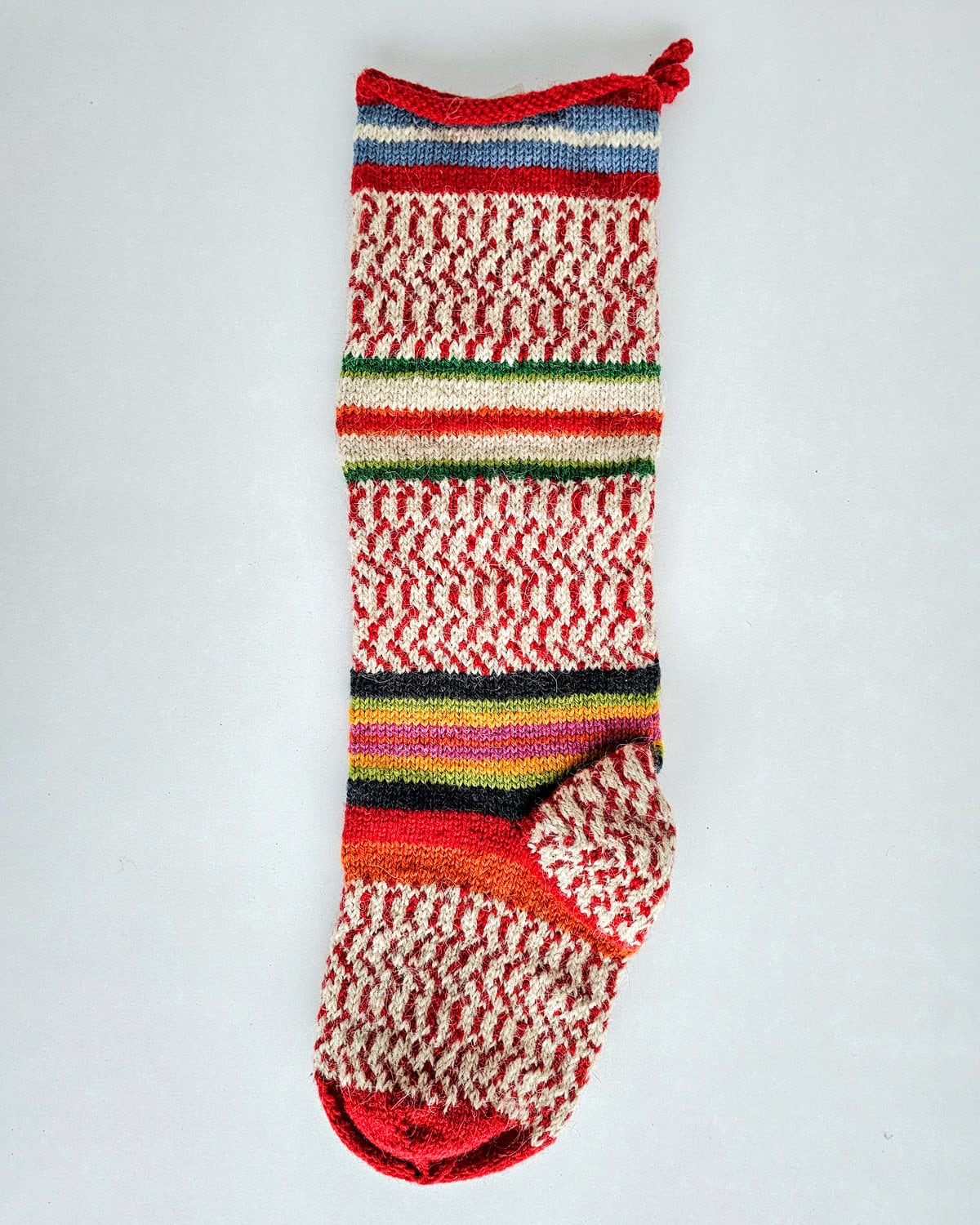 Artisan holiday stocking featuring bold stripes in multiple colors