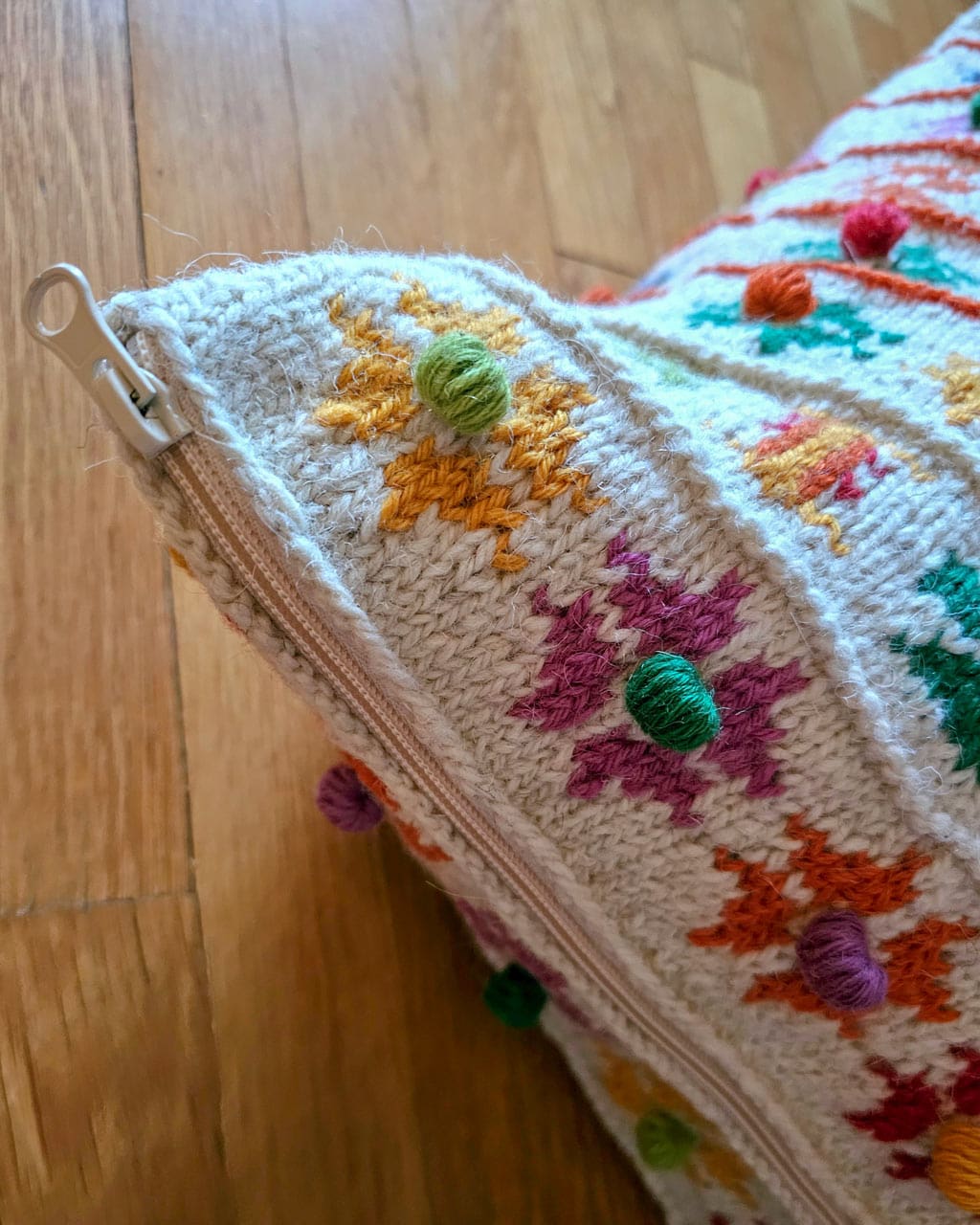 Close-up of fair trade handcrafted flower motifs and pom-poms on handmade pillow cover