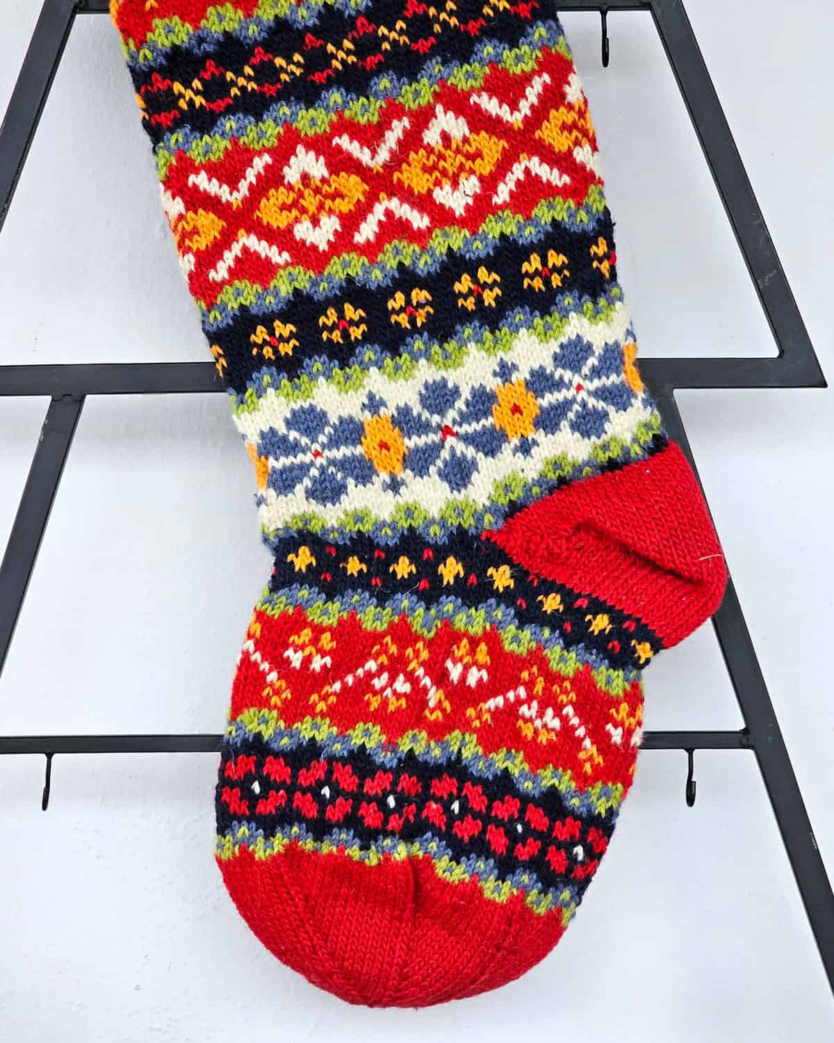 Handmade Christmas stocking with traditional Bosnian knitting design in red, white, blue, green, and yellow