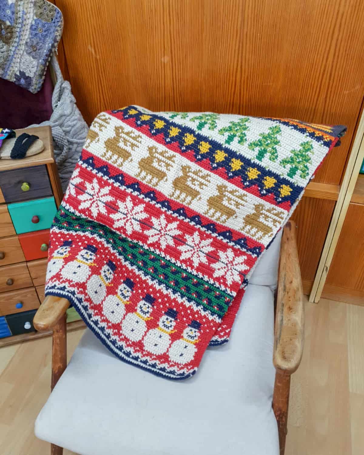 Fair trade hand-crocheted Christmas blanket with snowflakes, reindeer, and tree pattern in red, green, and white colors