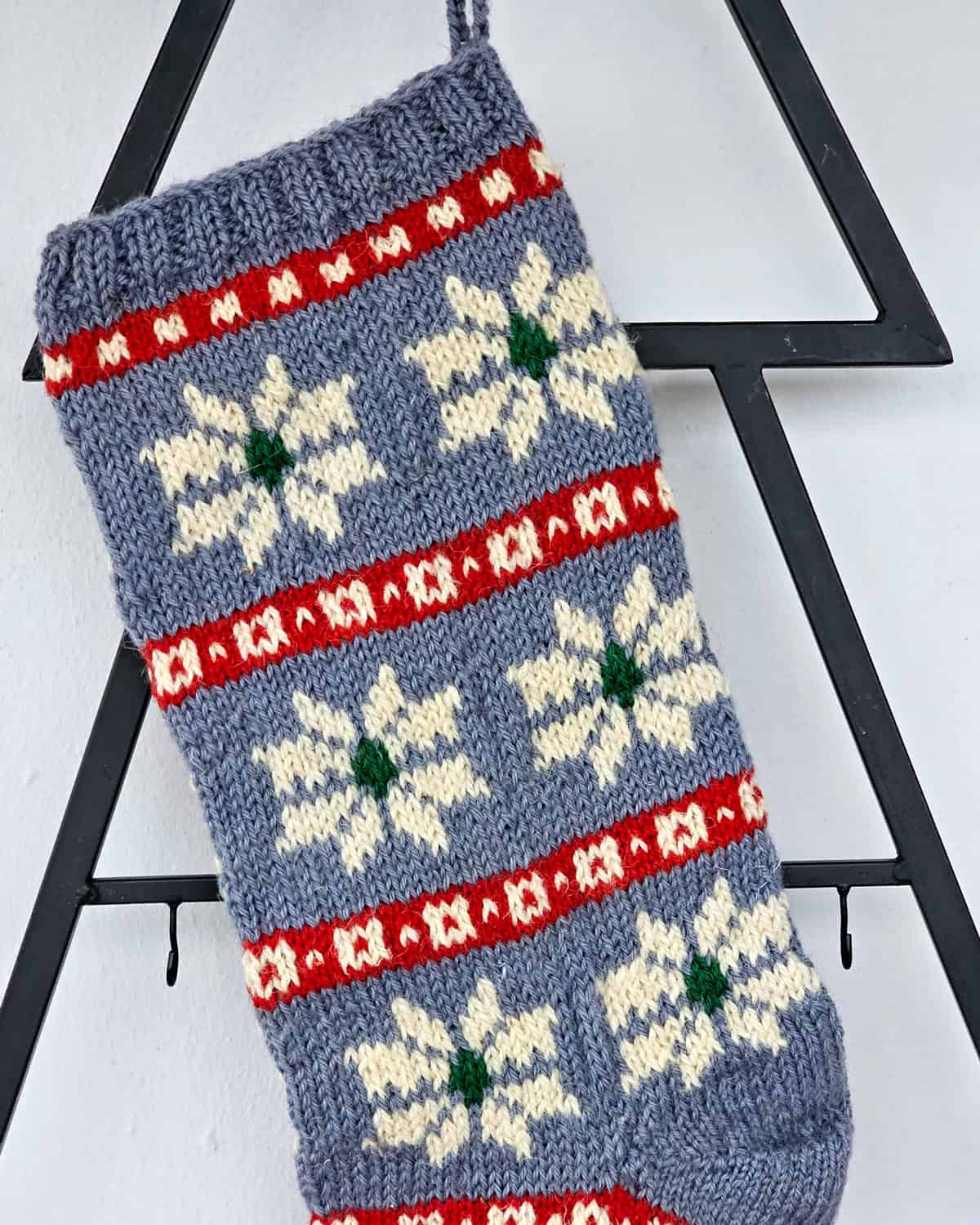 Handmade knitted Christmas stocking with snowflakes in blue, red, and white