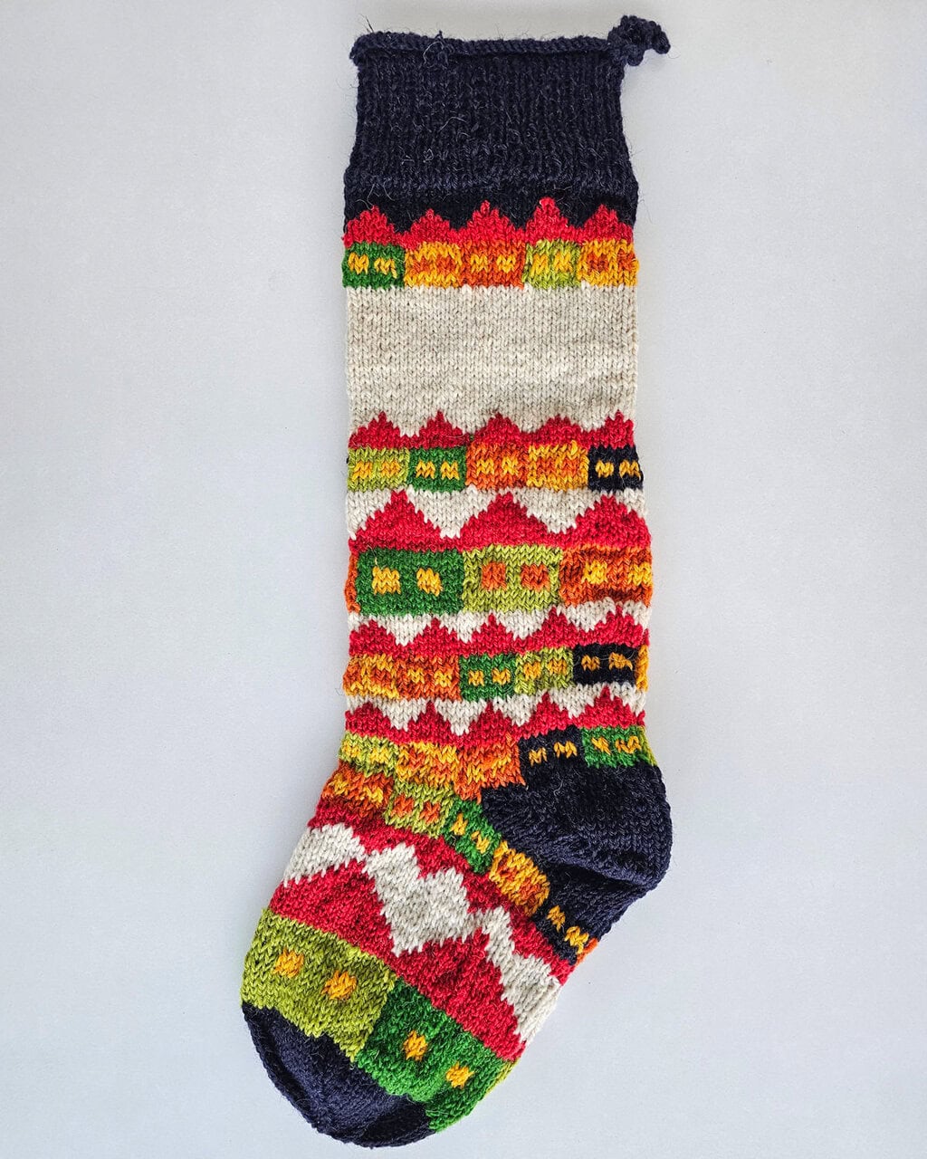 Hand-knitted multicolor Christmas stocking with traditional holiday village
