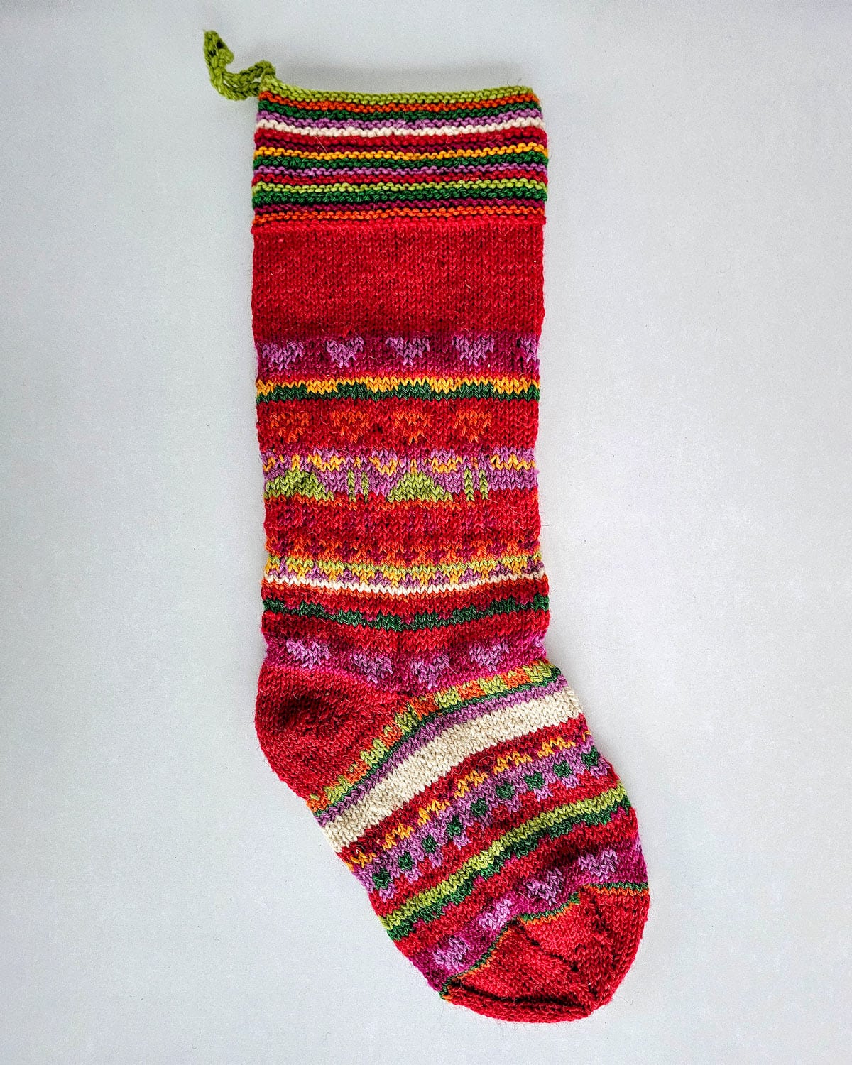 Hand-knitted Christmas stocking with colorful stripes and heart motifs