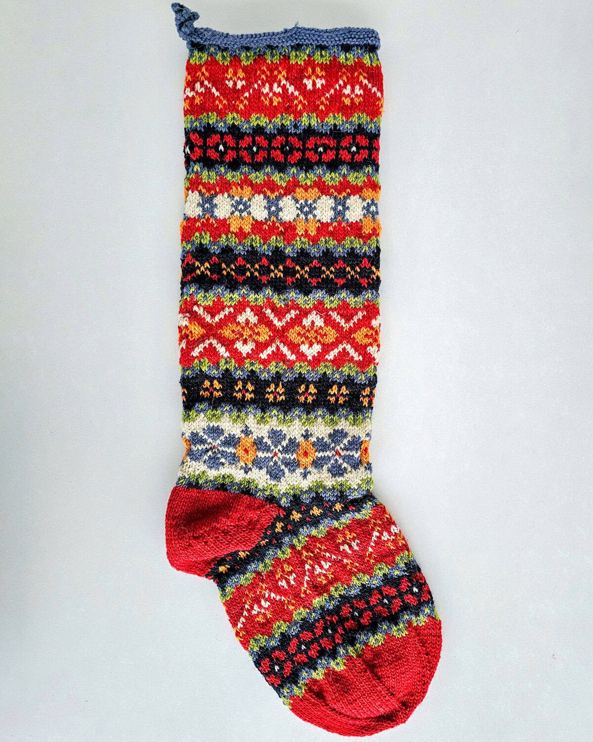 Hand-knit Christmas stocking with red heel and multicolor jacquard Fair-Trade design