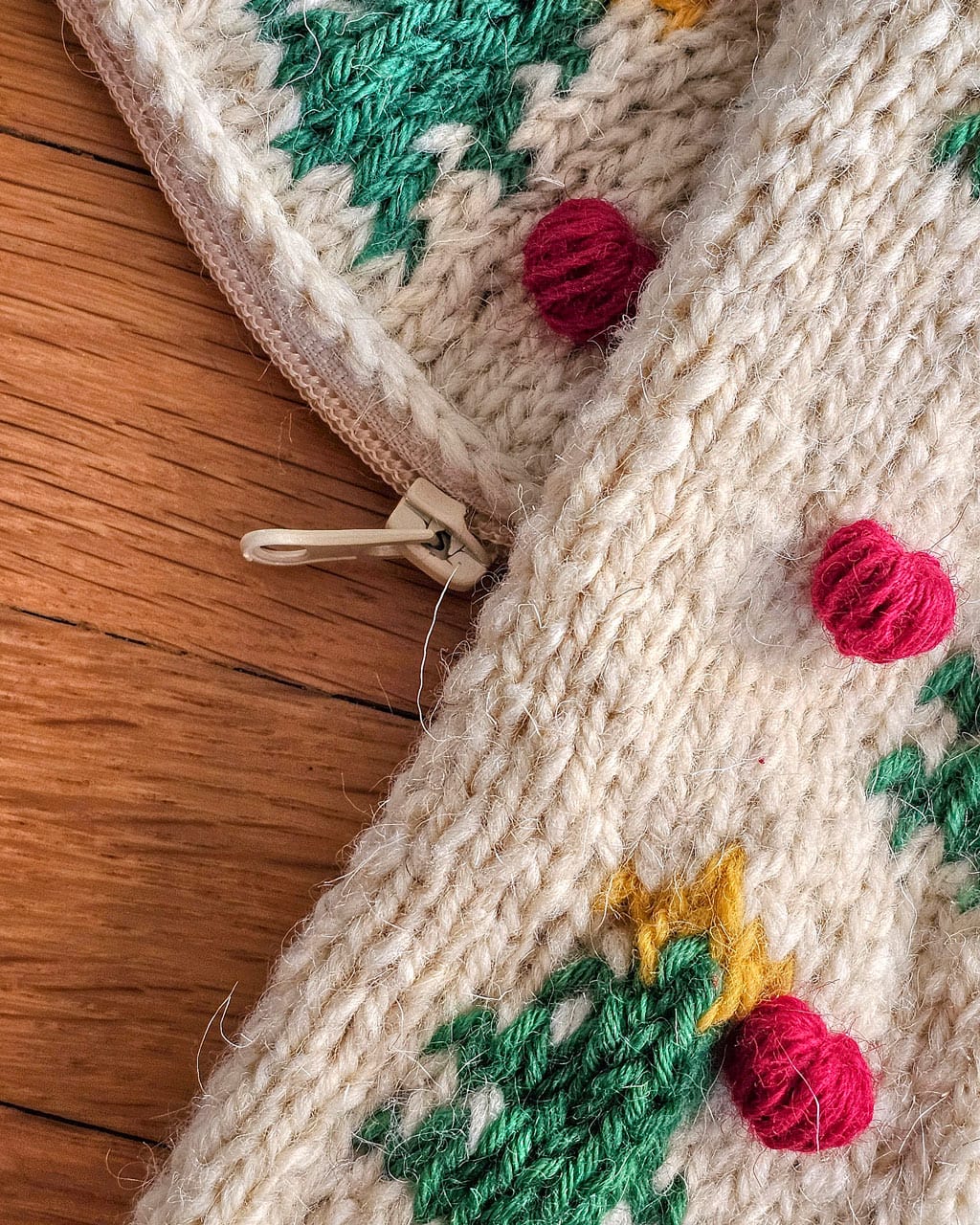 Close-up of knitted Christmas pillow with tree and pom-pom design