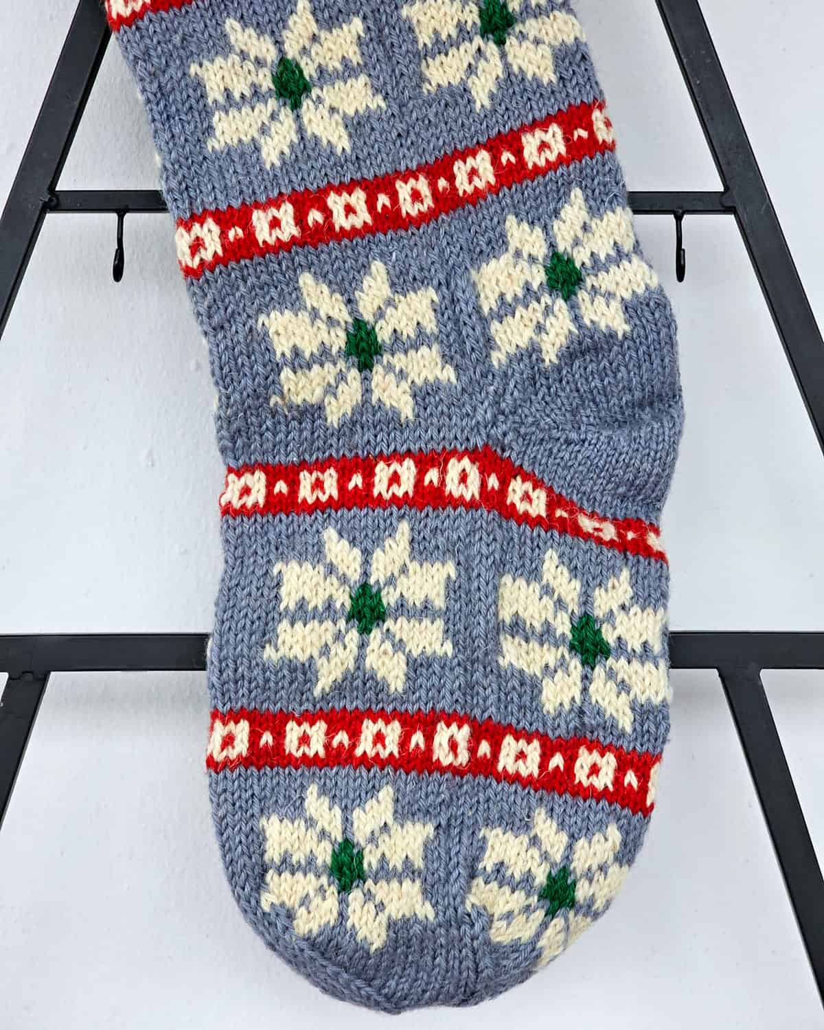 Decorative Christmas tree stocking with white snowflake motif on blue stocking with red and green details.