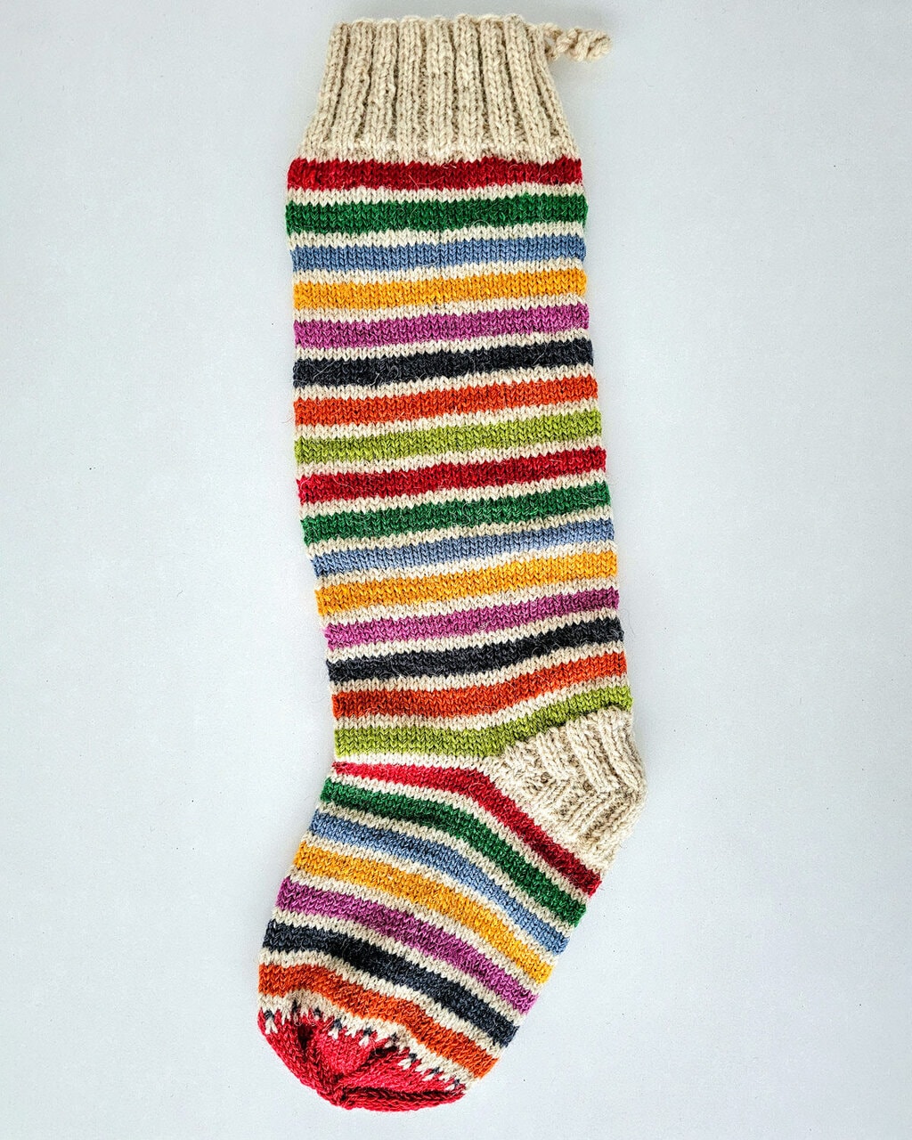 Festive holiday stocking in red, green, white stripes with tree design