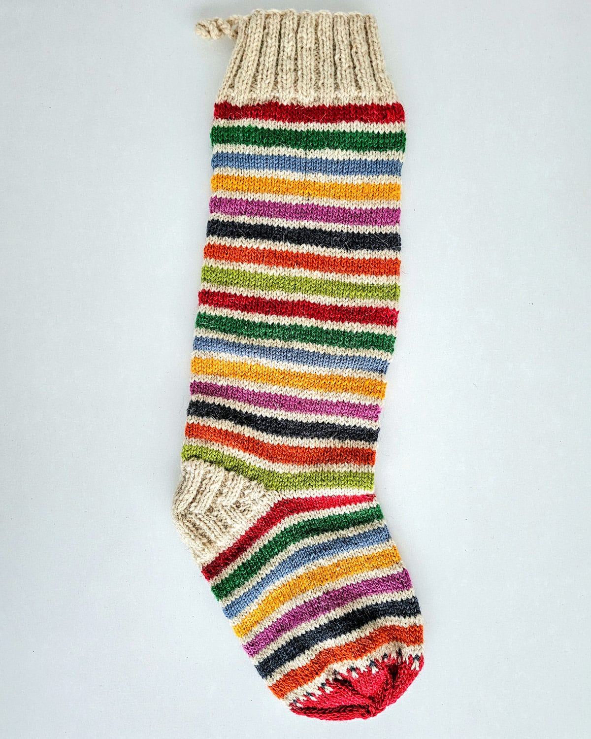 Festive holiday stocking in red, green, white stripes with tree design