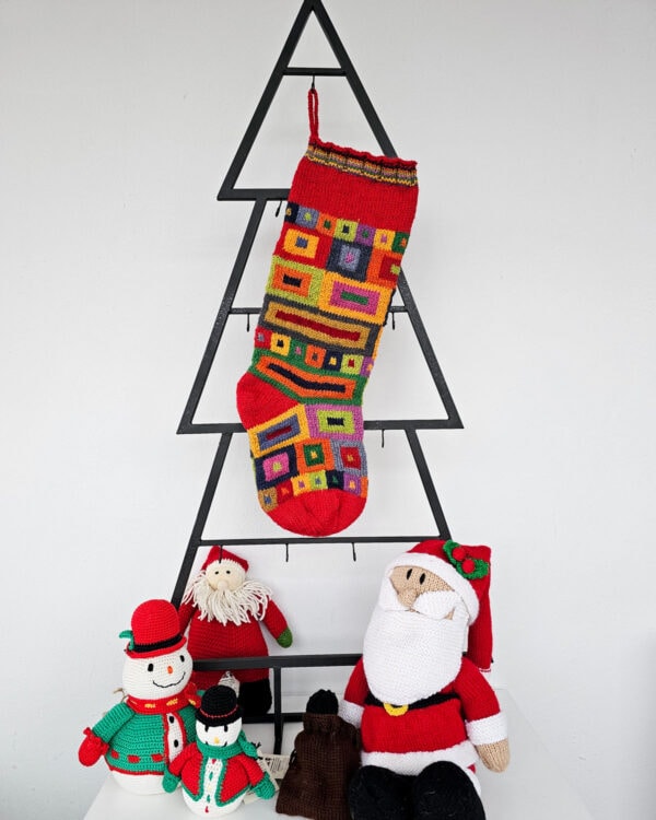 knitted Christmas stocking with vibrant square and rectangular patterns, ideal for personalization.