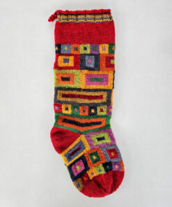 Handmade Christmas stocking with a bold, geometric design in multiple colors including red, green, and yellow.