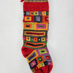 Handmade Christmas stocking with a bold, geometric design in multiple colors including red, green, and yellow.