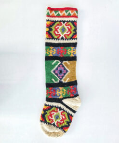 Handmade crochet Christmas stocking featuring bold tapestry-style geometric and floral patterns in vibrant colors.