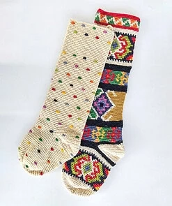 Set of two handmade crochet Christmas stockings featuring multicolored polka dots and a vibrant tapestry-style woven pattern.
