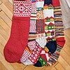 Five red themed knitted Christmas stockings with various patterns.