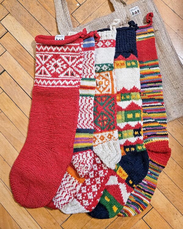 Five red themed knitted Christmas stockings with various patterns.