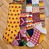 Five yellow themed knitted Christmas stockings with various patterns.