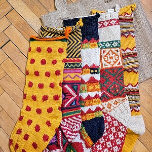 Five yellow themed knitted Christmas stockings with various patterns.