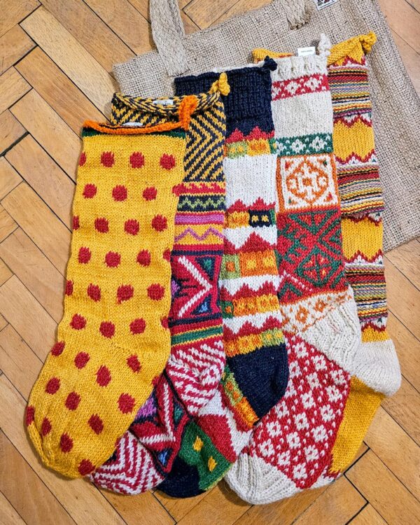 Five yellow themed knitted Christmas stockings with various patterns.