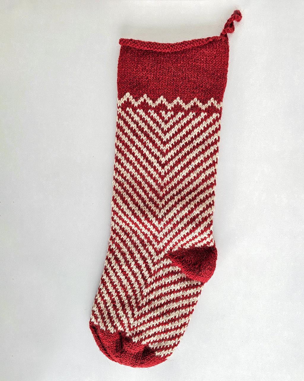 Fair trade artisanal Christmas stocking in red and cream zigzag knit design.
