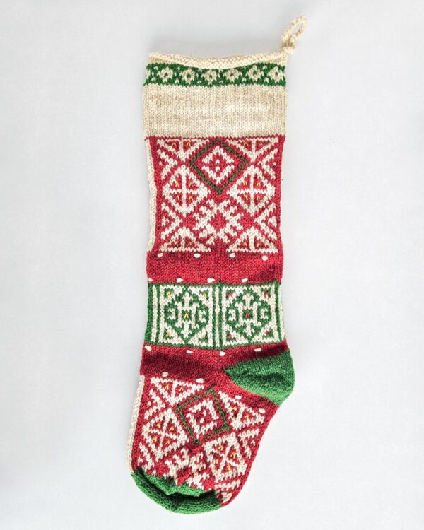 Hand-knitted Fair Trade Christmas stocking in red, green, and cream with traditional pattern.
