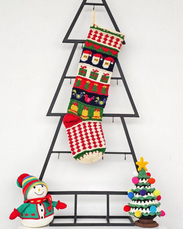 Fair-trade Christmas stocking featuring Santa, gifts, and bells in multicolor design.