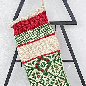 Traditional hand-knitted Christmas stocking in red, green, and cream with customizable embroidered name.