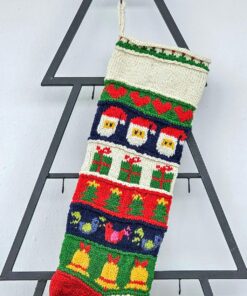 Close-up of the top part of a personalized Christmas stocking, hand-knitted with festive motifs.