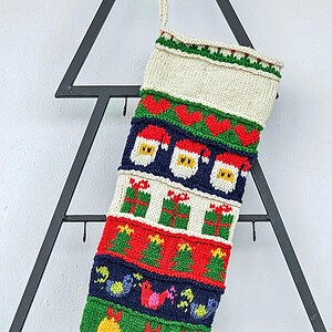 Close-up of the top part of a personalized Christmas stocking, hand-knitted with festive motifs.