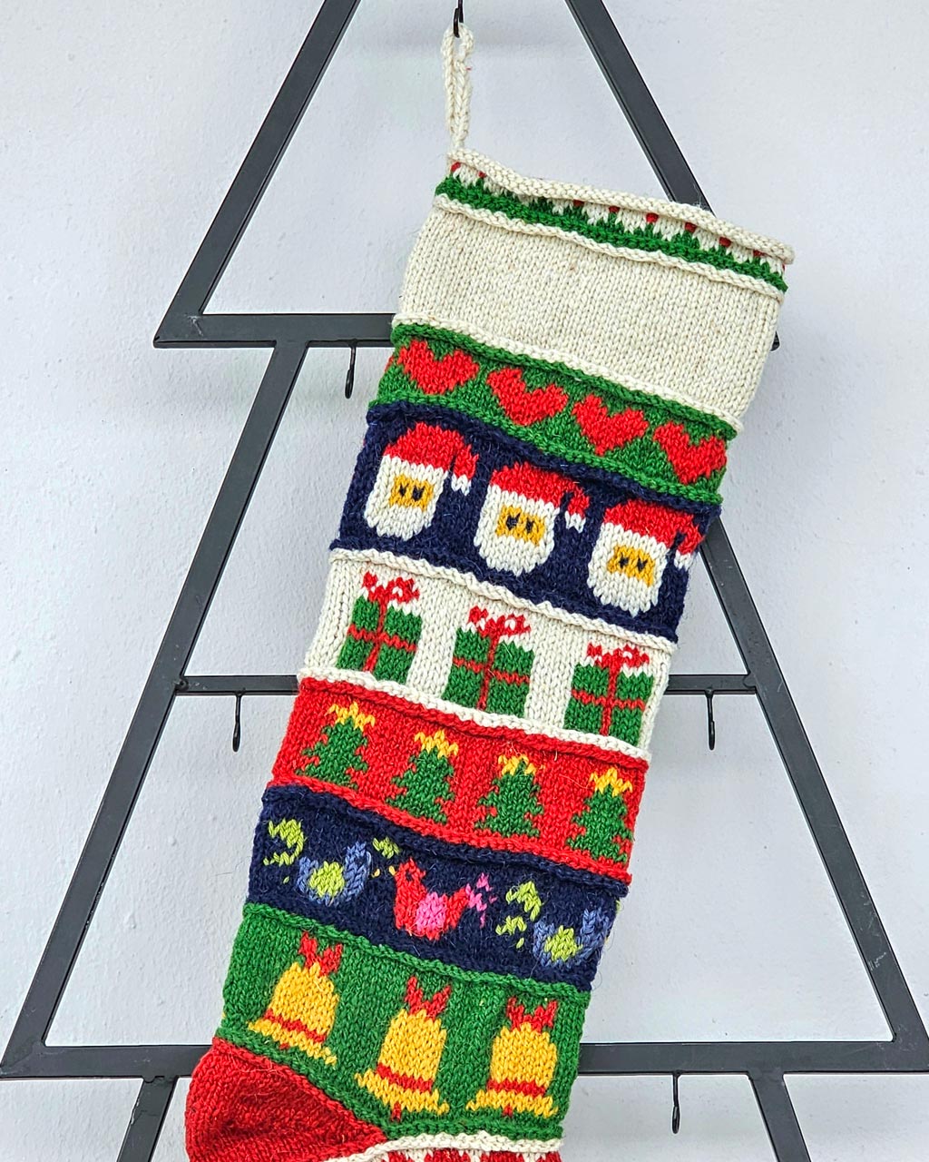 Close-up of the top part of a personalized Christmas stocking, hand-knitted with festive motifs.
