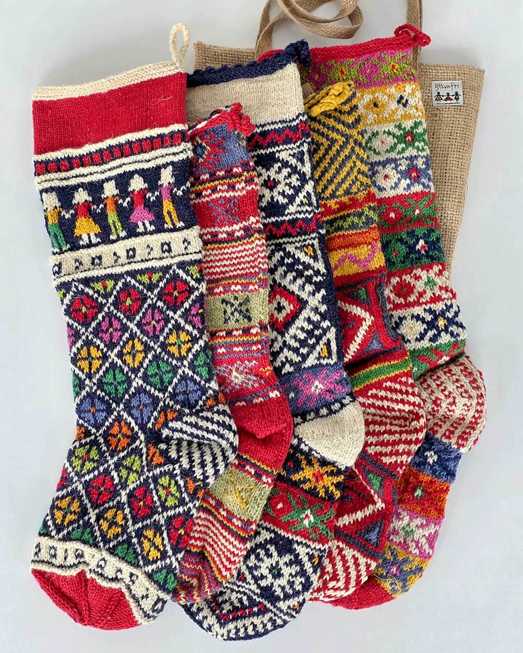 Five hand-knitted sustainable wool Christmas stockings made by women artisans, shown together as a set